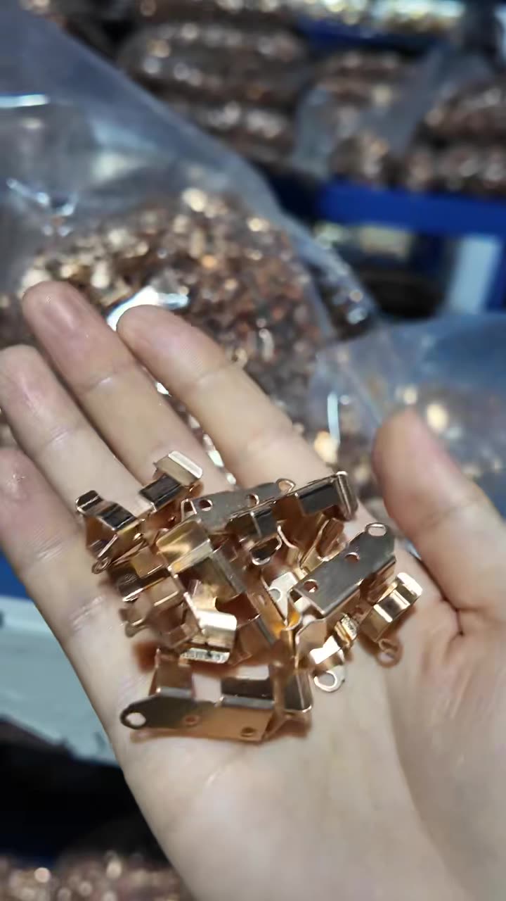 Brass terminals held in a gloved hand after stamping