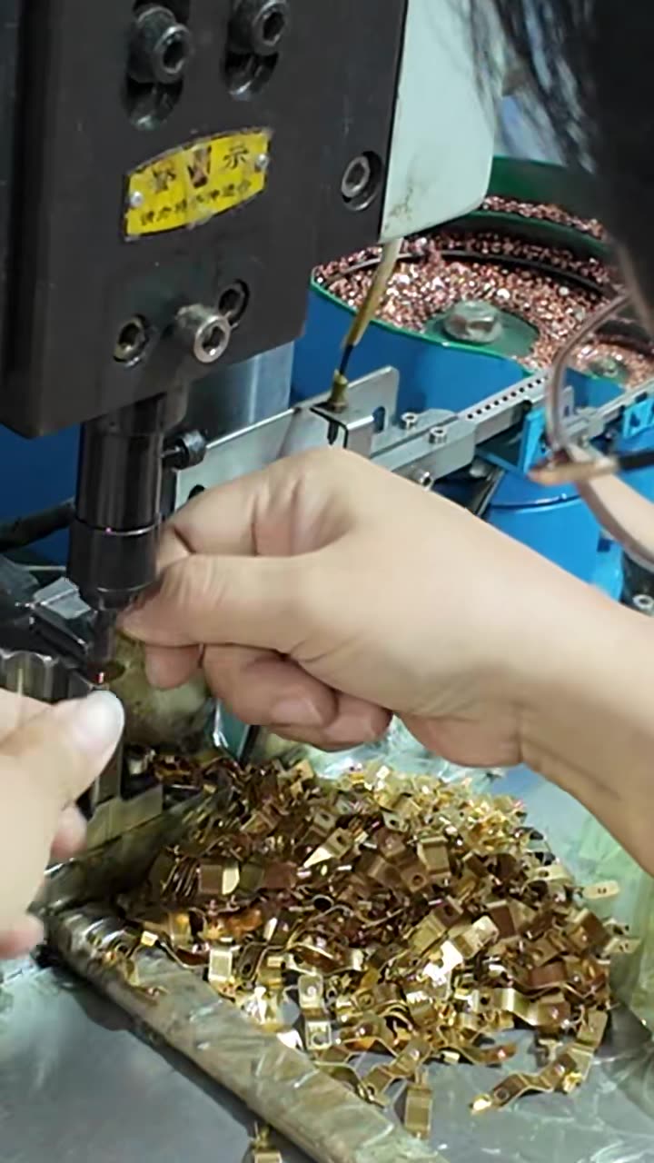 Operator checking stamped brass parts at the machine